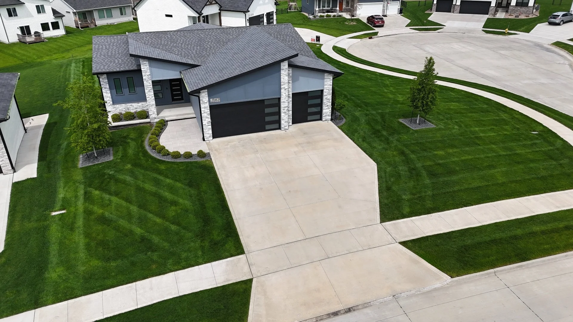 A well-maintained, vibrant green lawn with striped mowing patterns and clean landscaping.