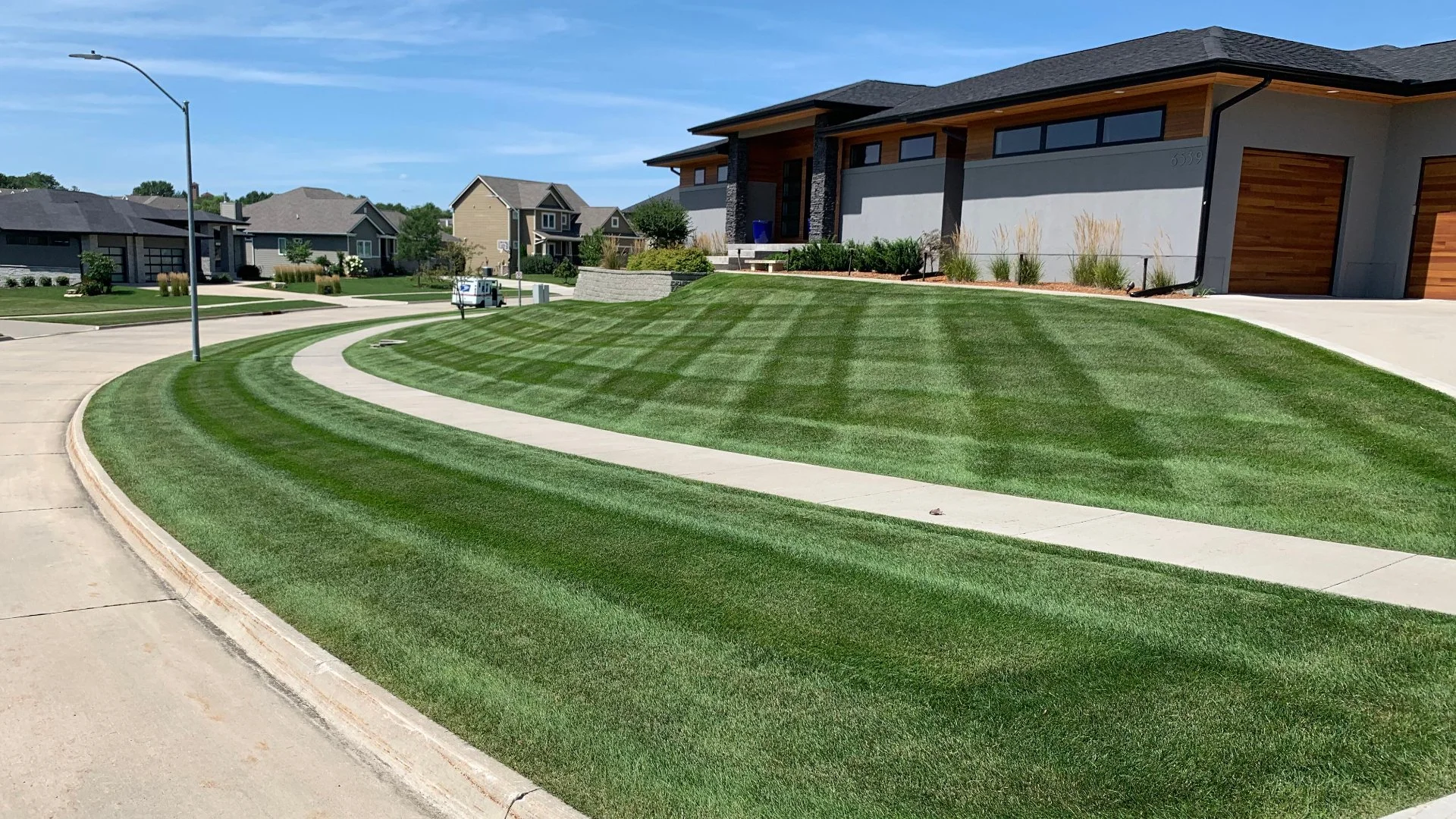 A well-maintained, vibrant green lawn with striped mowing patterns and clean landscaping.