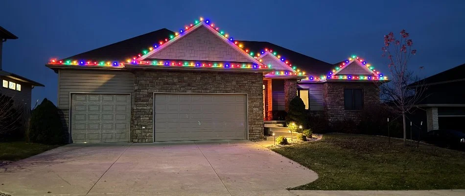 Colorful Christmas lights along a house's roofline in Waukee, IA.
