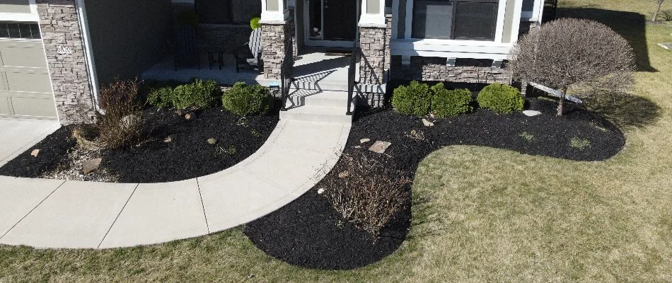 Mulch beds with plants around a front walkway in Waukee, IA.