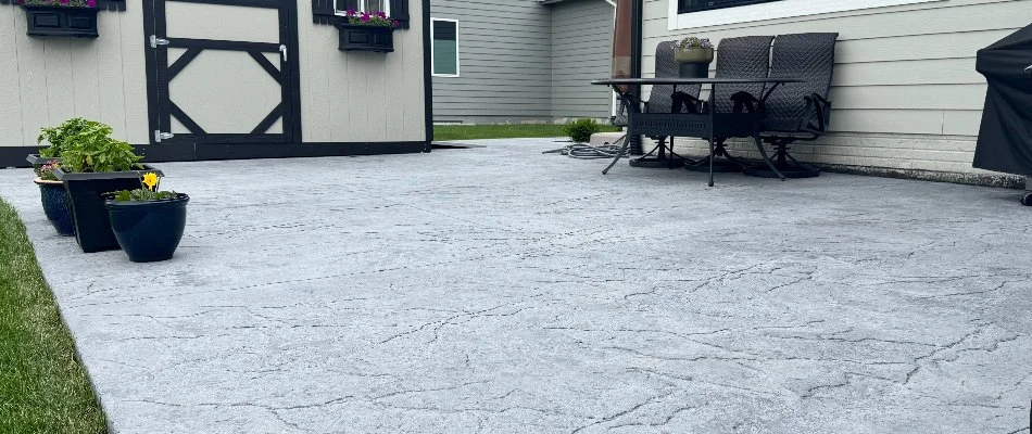 Stamped concrete patio in Waukee, IA, with plants and chairs.