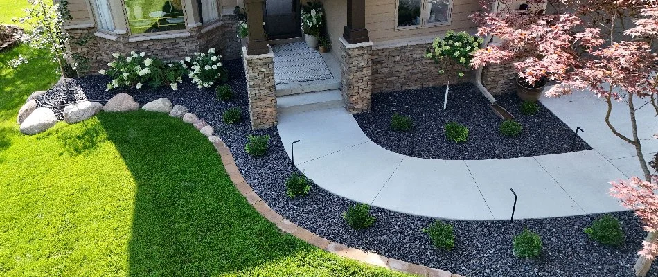 Walkway and landscape in Waukee, IA, with rocks, flowers, and shrubs.