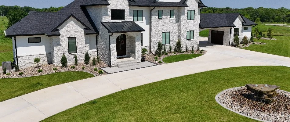 Large, white house in Adel, IA, with a driveway and manicured landscaping.