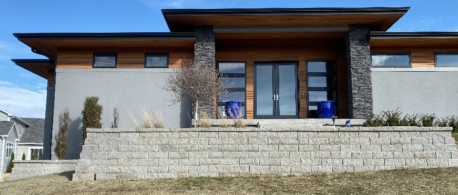 Modern home with stone retaining wall and landscaped front yard in Waukee, IA.